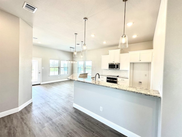 kitchen featuring light stone counters, oven, white cabinetry, decorative light fixtures, and tasteful backsplash