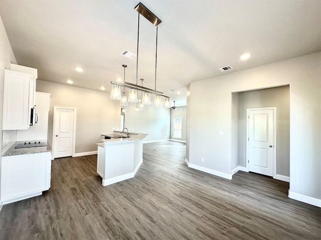 kitchen with white cabinets, pendant lighting, dark hardwood / wood-style flooring, and a kitchen island with sink