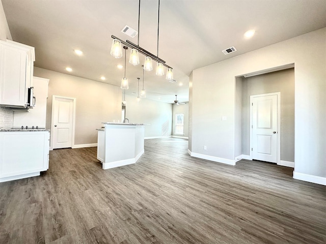 kitchen with white cabinetry, ceiling fan, hanging light fixtures, a center island with sink, and dark hardwood / wood-style flooring