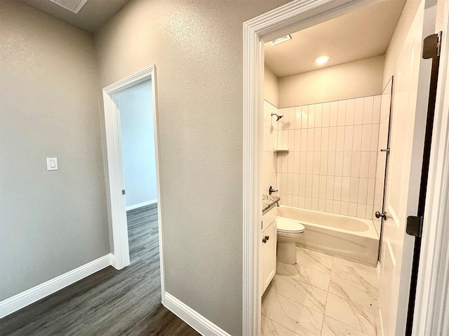 bathroom with toilet, tiled shower / bath combo, and hardwood / wood-style floors