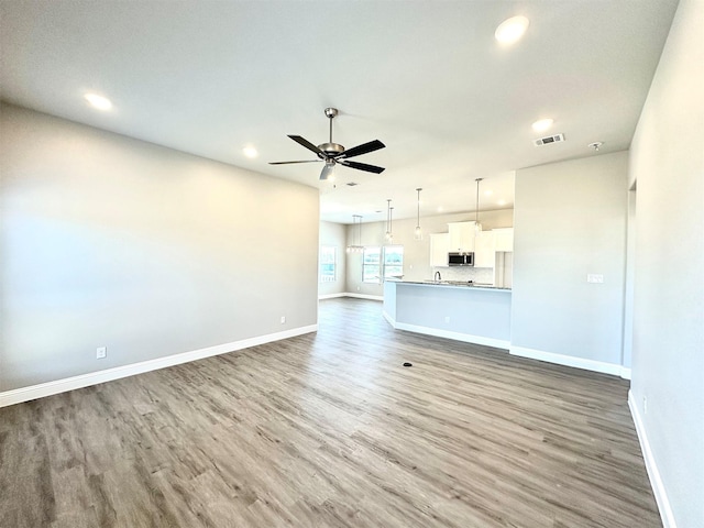 unfurnished living room with ceiling fan and hardwood / wood-style flooring