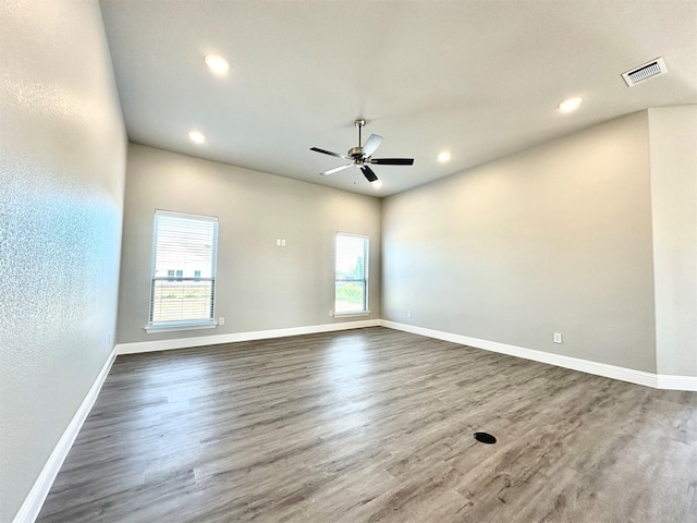 spare room featuring dark wood-type flooring, ceiling fan, and plenty of natural light