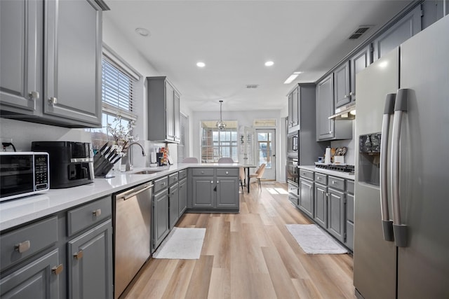 kitchen featuring sink, gray cabinets, decorative light fixtures, light hardwood / wood-style floors, and stainless steel appliances