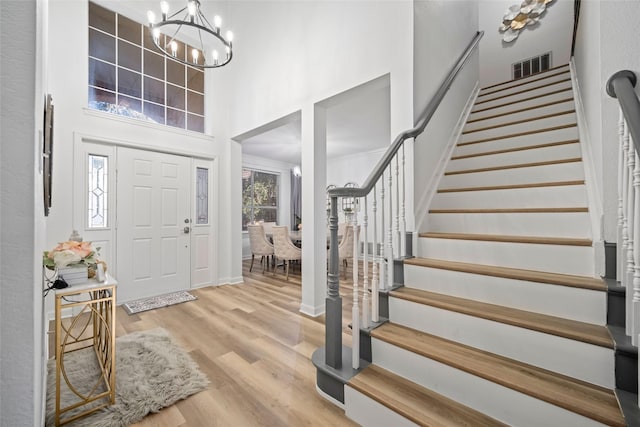 foyer with hardwood / wood-style floors, a high ceiling, and an inviting chandelier