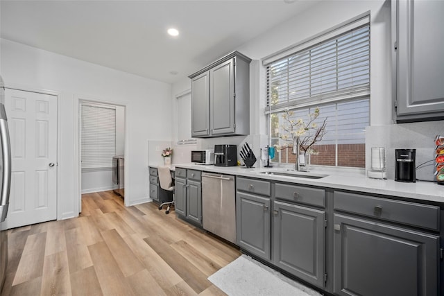 kitchen with dishwasher, gray cabinets, light hardwood / wood-style floors, and sink