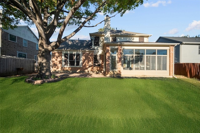 rear view of property featuring a lawn and a sunroom