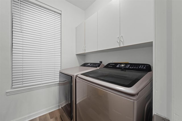 clothes washing area with washer and clothes dryer, cabinets, and light hardwood / wood-style flooring