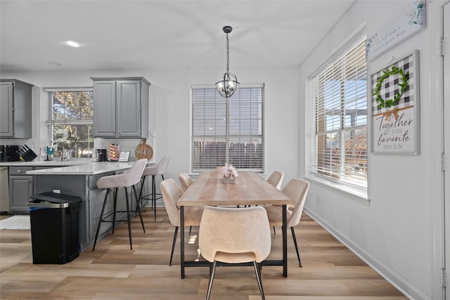 dining area with light hardwood / wood-style floors, a wealth of natural light, and a notable chandelier