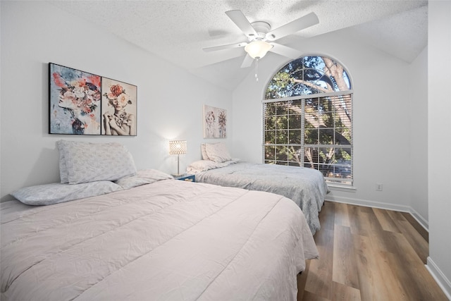 bedroom with a textured ceiling, ceiling fan, vaulted ceiling, and hardwood / wood-style flooring