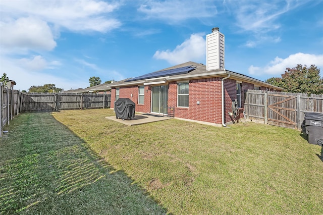 back of house featuring a lawn, a patio, and solar panels