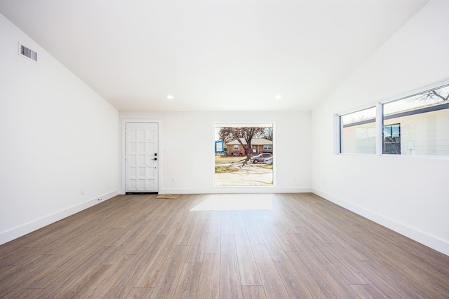 unfurnished room featuring lofted ceiling and light wood-type flooring