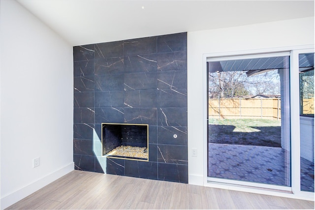 interior details featuring wood-type flooring and a tiled fireplace