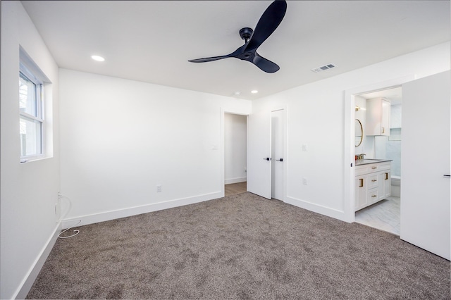 unfurnished bedroom with light carpet, ensuite bathroom, and ceiling fan