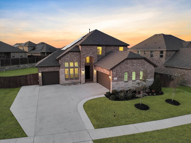 view of front of property with a yard, a garage, and solar panels