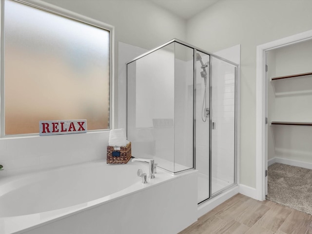 bathroom featuring plus walk in shower and wood-type flooring