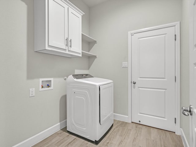 laundry area featuring washer / dryer, light wood-type flooring, and cabinets