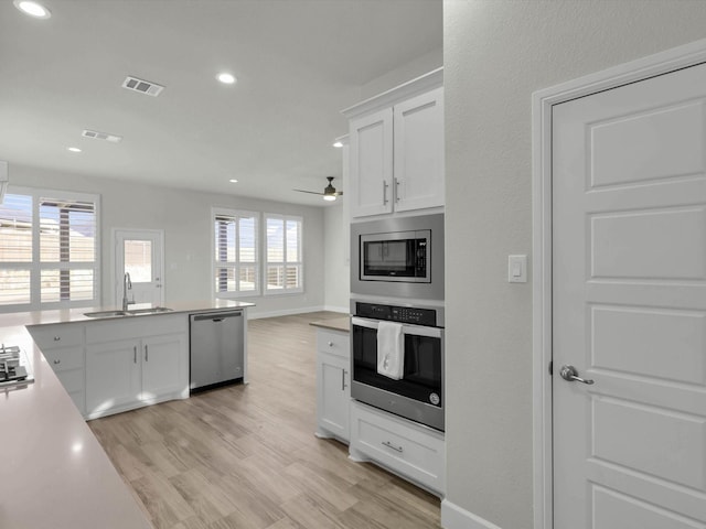 kitchen featuring appliances with stainless steel finishes, light wood-type flooring, white cabinets, and sink