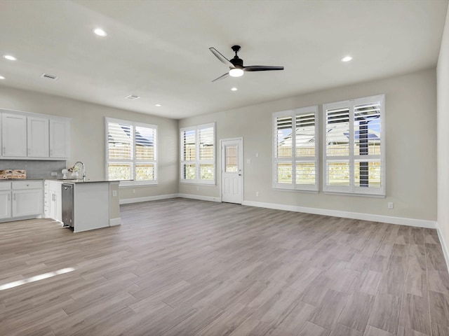 unfurnished living room with sink, ceiling fan, and light hardwood / wood-style floors