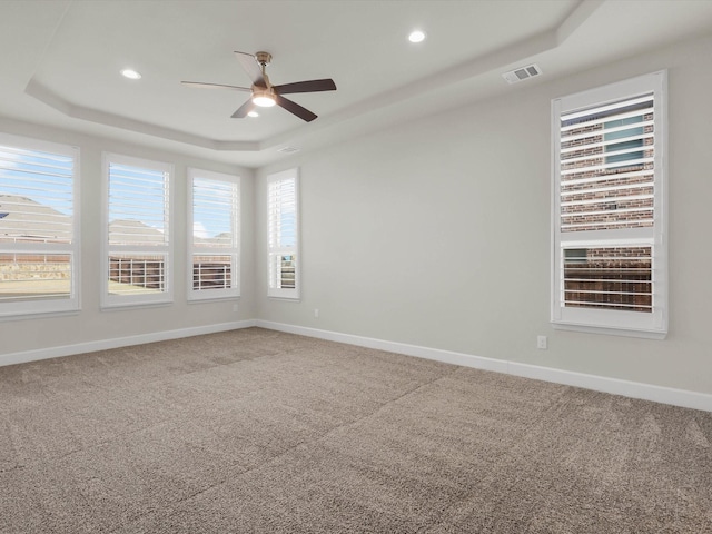 unfurnished room featuring ceiling fan, a tray ceiling, and carpet