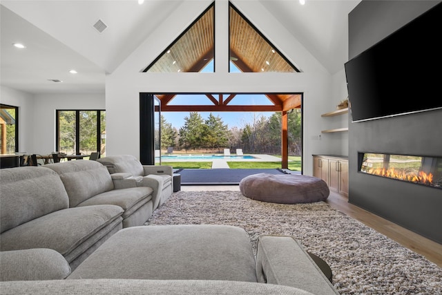 living room featuring high vaulted ceiling and light hardwood / wood-style flooring