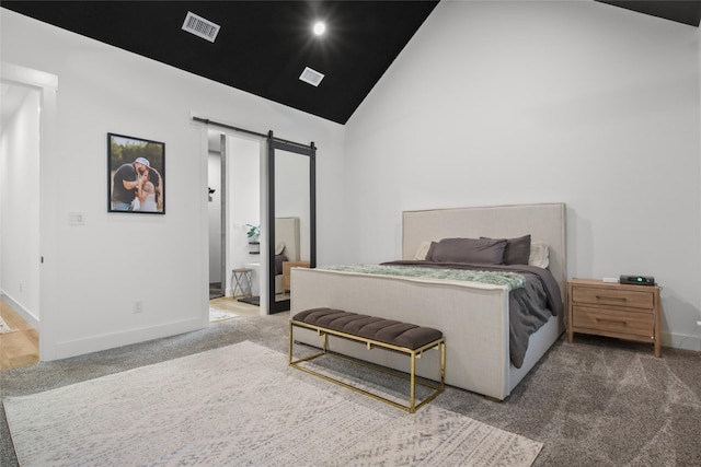 carpeted bedroom featuring a barn door, ensuite bathroom, and high vaulted ceiling