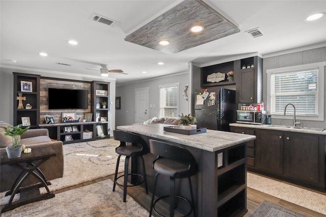 kitchen featuring black fridge, a breakfast bar, ceiling fan, sink, and a kitchen island