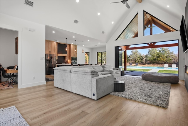 living room with beamed ceiling, ceiling fan, high vaulted ceiling, and light hardwood / wood-style flooring