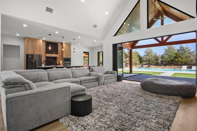 living room with light hardwood / wood-style flooring and high vaulted ceiling