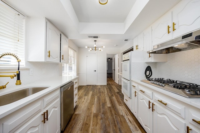 kitchen featuring dark wood-type flooring, an inviting chandelier, sink, white cabinetry, and stainless steel appliances