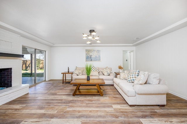 living room featuring a fireplace, wood-type flooring, and a notable chandelier