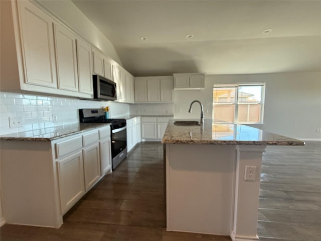 kitchen with sink, an island with sink, appliances with stainless steel finishes, light stone counters, and white cabinetry