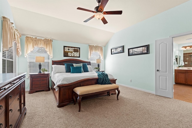 carpeted bedroom featuring lofted ceiling, connected bathroom, ceiling fan, and multiple windows