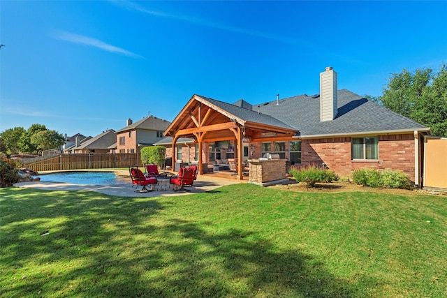 rear view of property with a lawn, an outdoor kitchen, an outdoor living space, a fenced in pool, and a patio