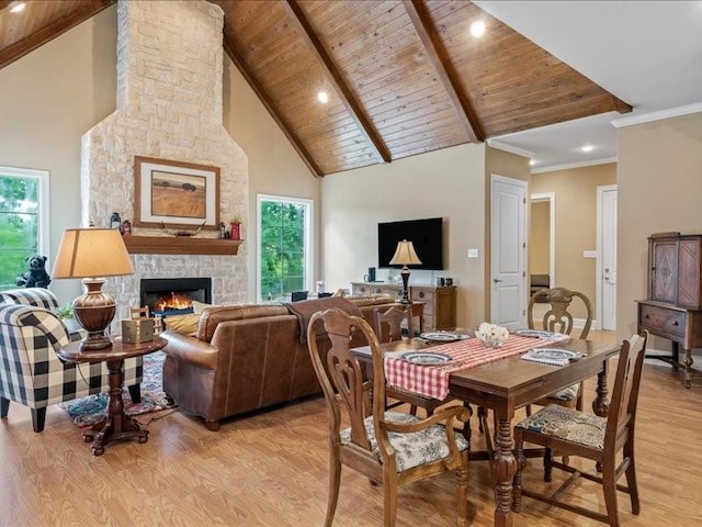 dining area with light wood-type flooring, high vaulted ceiling, and a fireplace