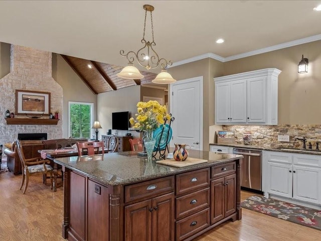 kitchen featuring stainless steel dishwasher, white cabinetry, sink, and a fireplace