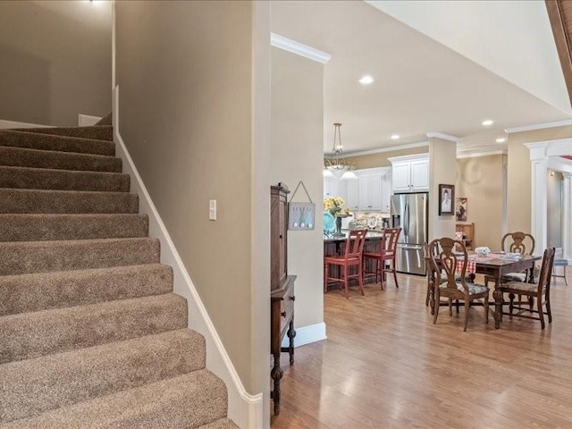 stairway with ornamental molding, decorative columns, and hardwood / wood-style flooring