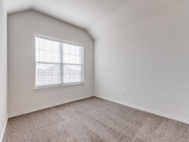 carpeted empty room featuring vaulted ceiling