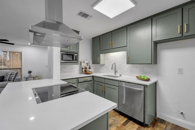 kitchen with a sink, exhaust hood, visible vents, appliances with stainless steel finishes, and green cabinetry