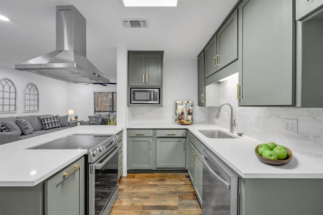 kitchen with a sink, visible vents, open floor plan, appliances with stainless steel finishes, and range hood