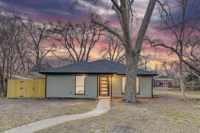 view of front of home with roof with shingles and a gate