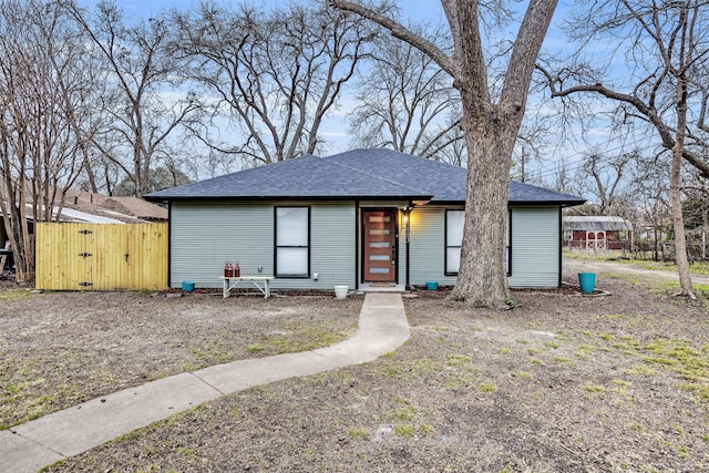 view of front of house featuring a shingled roof and a gate