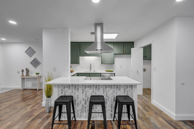 kitchen with a breakfast bar area, tasteful backsplash, light countertops, a sink, and green cabinetry