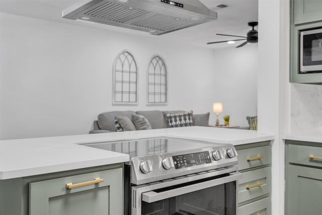 kitchen featuring ceiling fan, exhaust hood, light countertops, appliances with stainless steel finishes, and green cabinetry