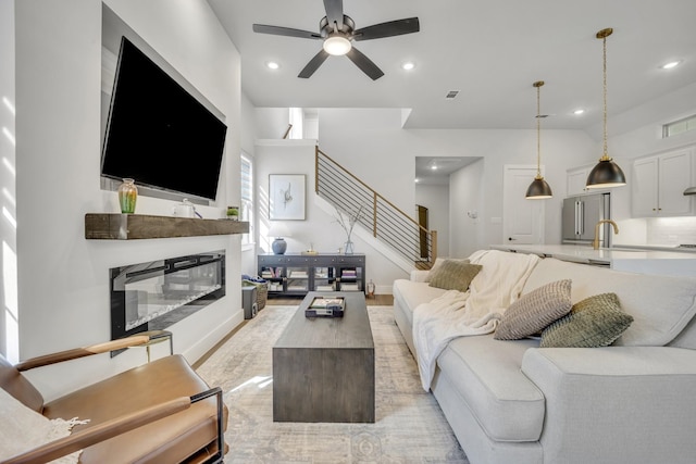 living room featuring ceiling fan, light hardwood / wood-style flooring, and sink