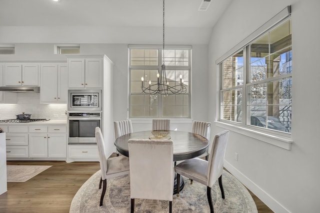 dining area featuring lofted ceiling, an inviting chandelier, and hardwood / wood-style flooring