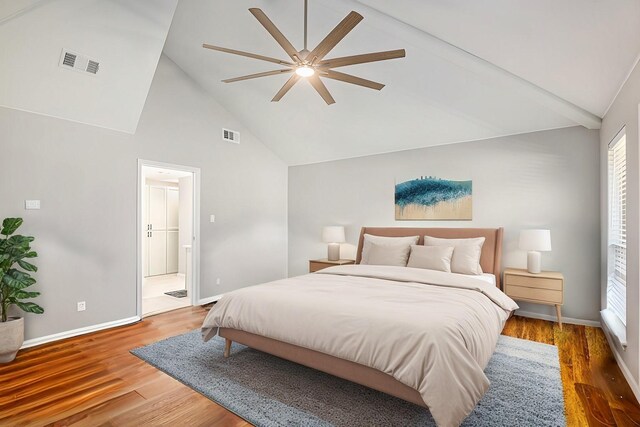 bedroom featuring ceiling fan, ensuite bathroom, high vaulted ceiling, and hardwood / wood-style flooring