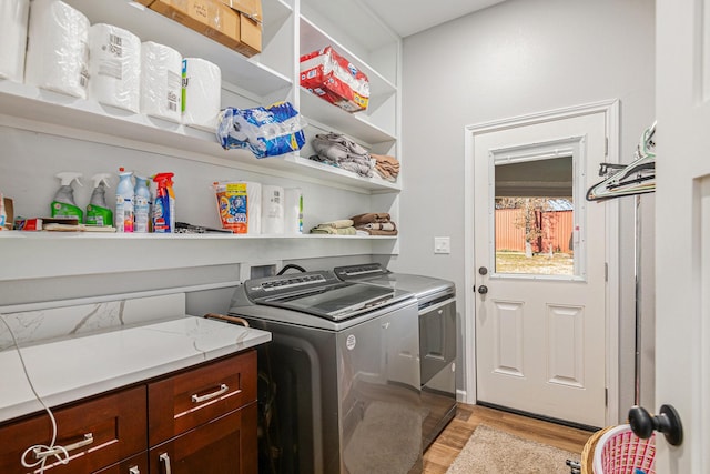 clothes washing area with light hardwood / wood-style flooring and washer and clothes dryer