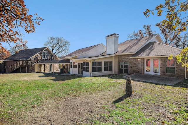 rear view of property with a lawn, french doors, and a sunroom