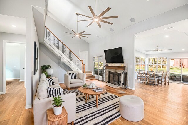 living room with high vaulted ceiling, ceiling fan, and light hardwood / wood-style flooring