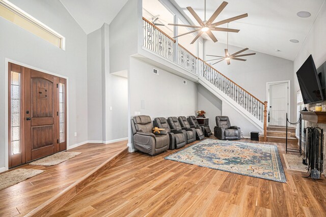 living room with ceiling fan, light hardwood / wood-style flooring, and high vaulted ceiling